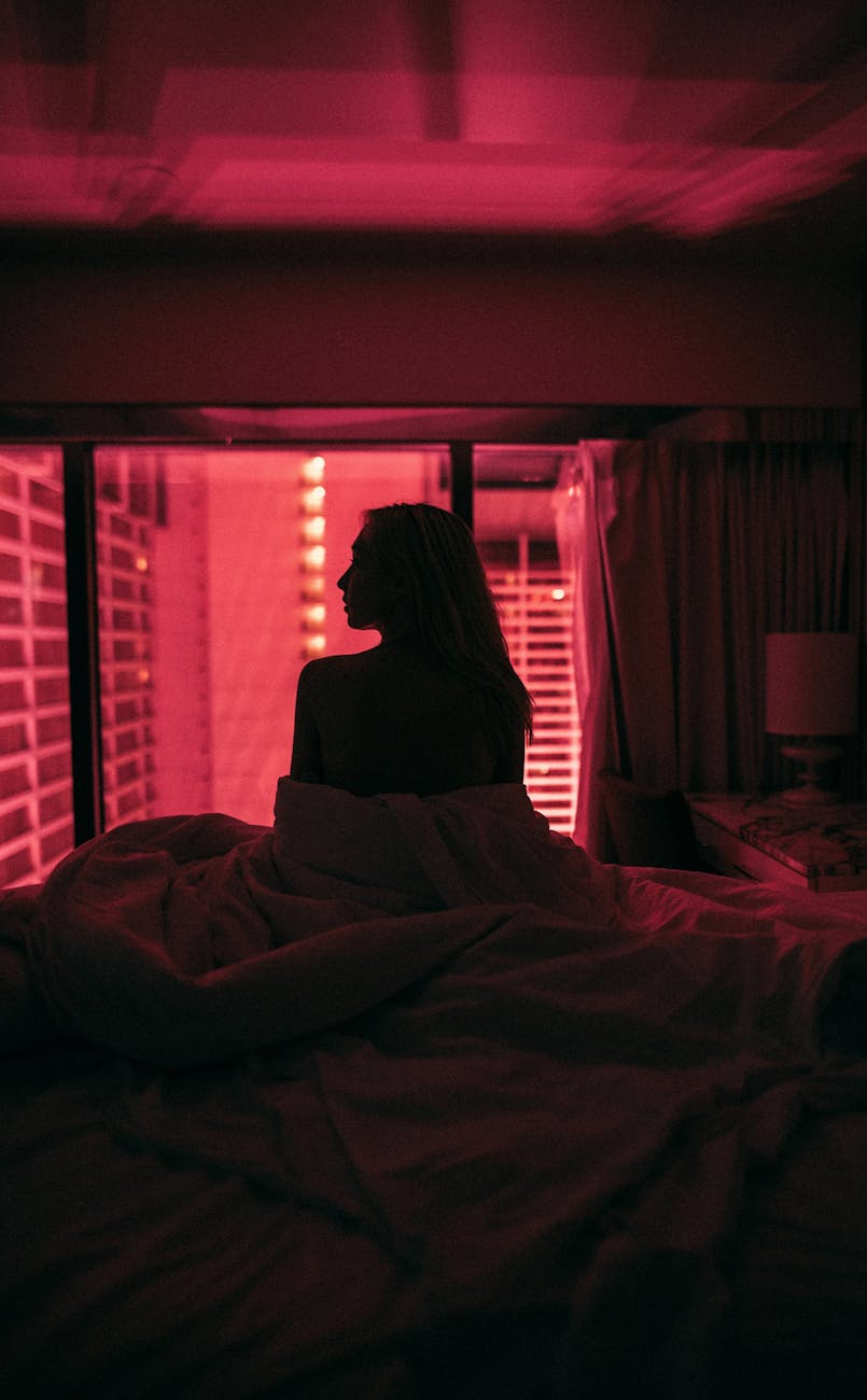 woman silhouette on bed in pink light