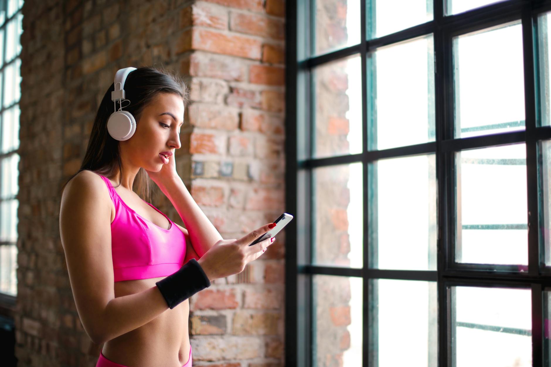 woman in pink sports bra while holding smartphone