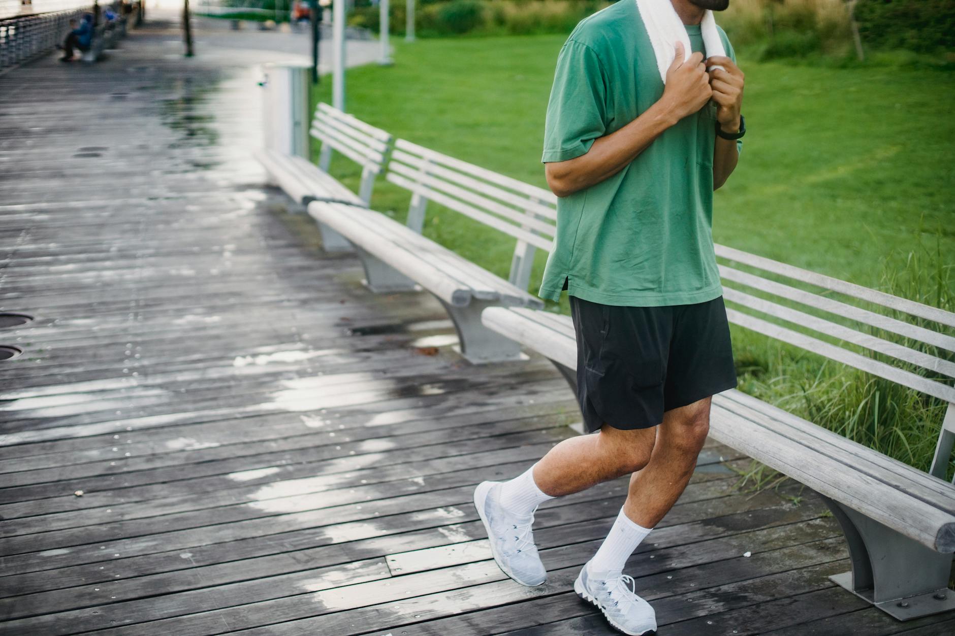 man in green t shirt jogging on boardwalk