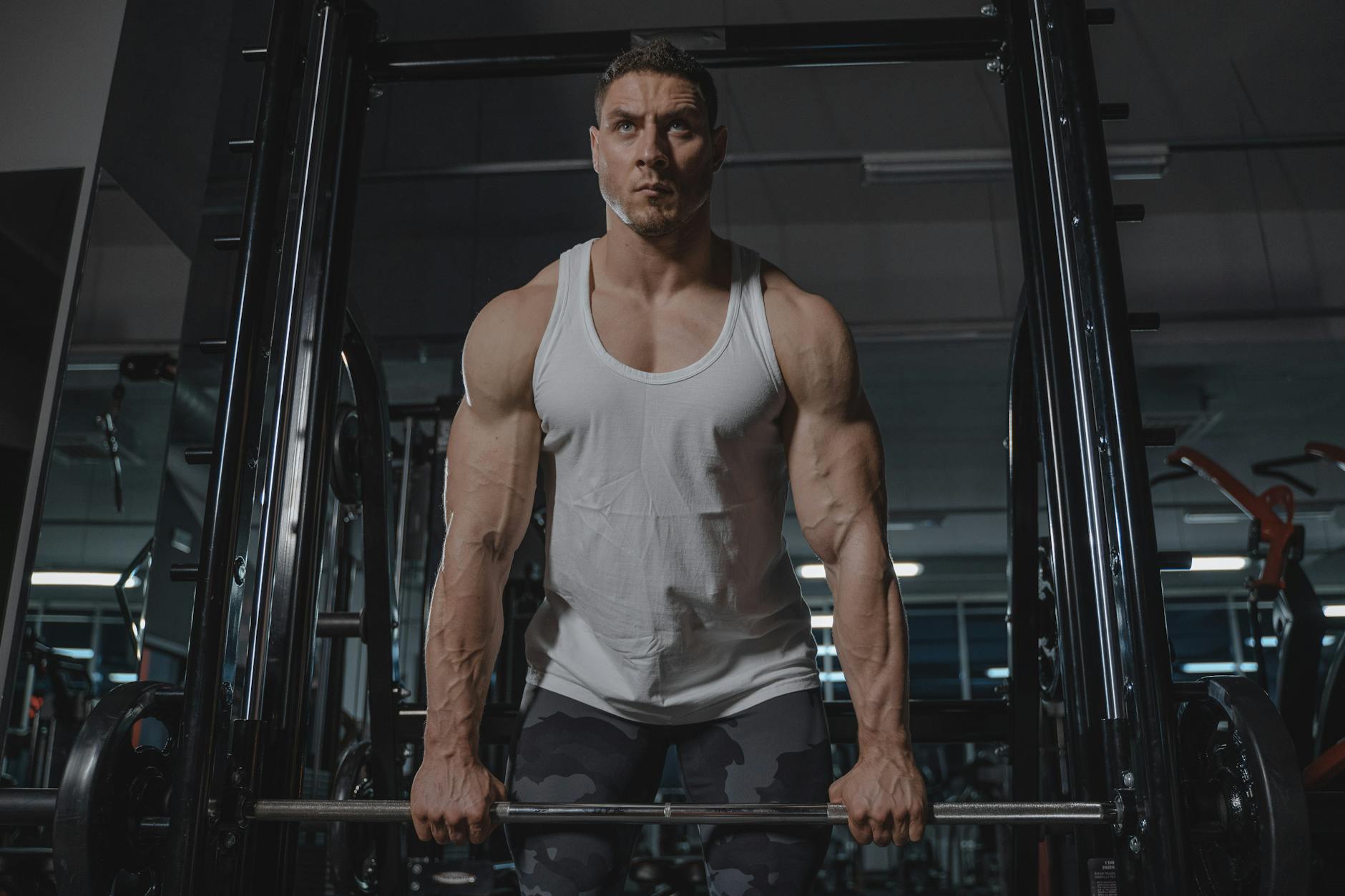 man in white tank top lifting weights