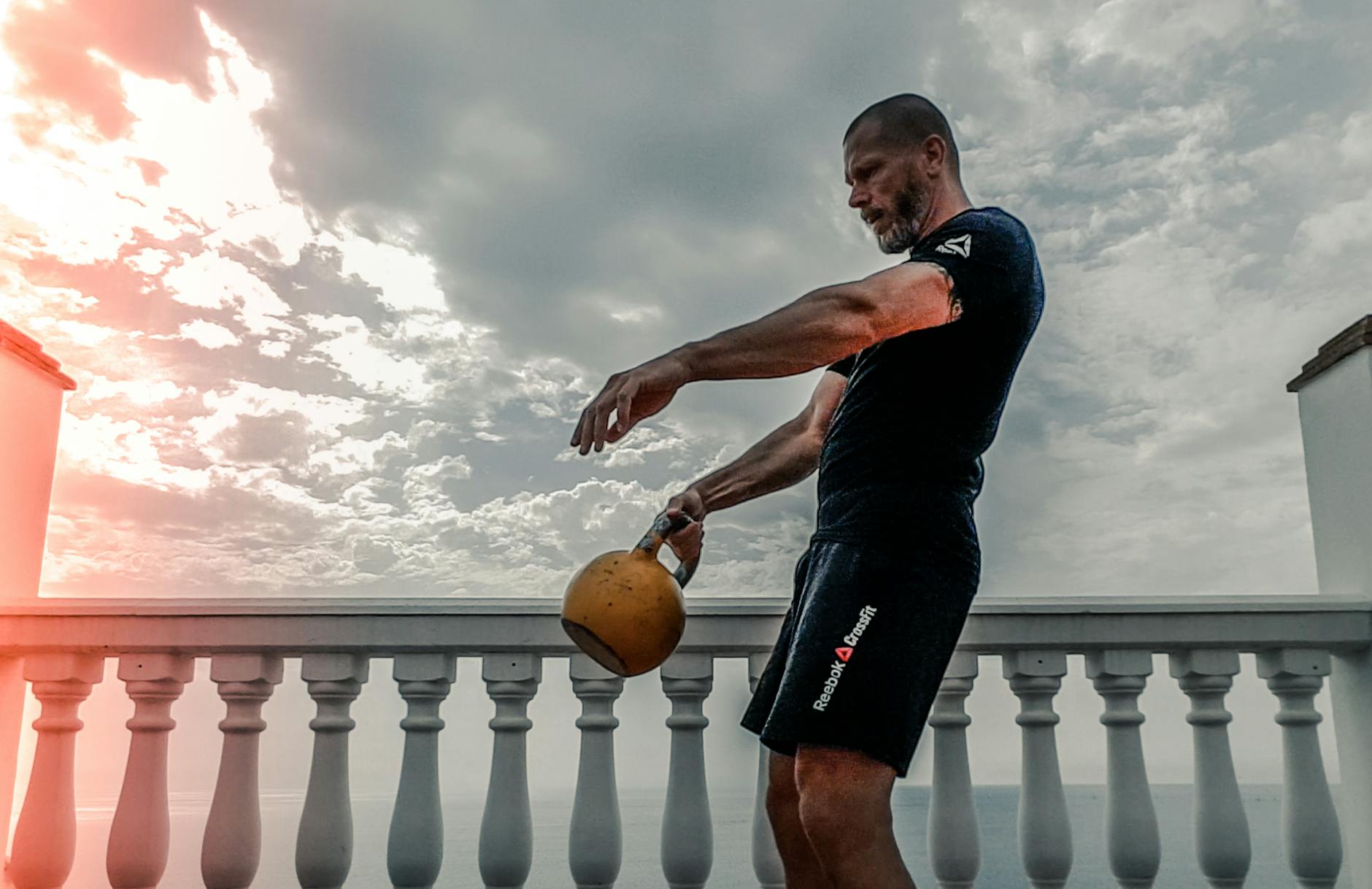 man in black shirt carrying kettle bell outdoors
