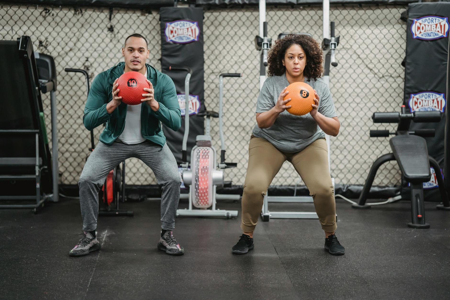 ethnic fitness trainer and plump woman squatting with fitness balls