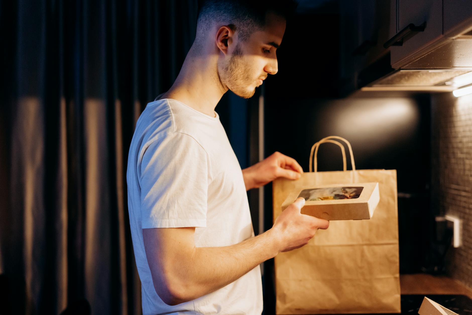 a man in white crew neck t shirt unpacking a paper bag