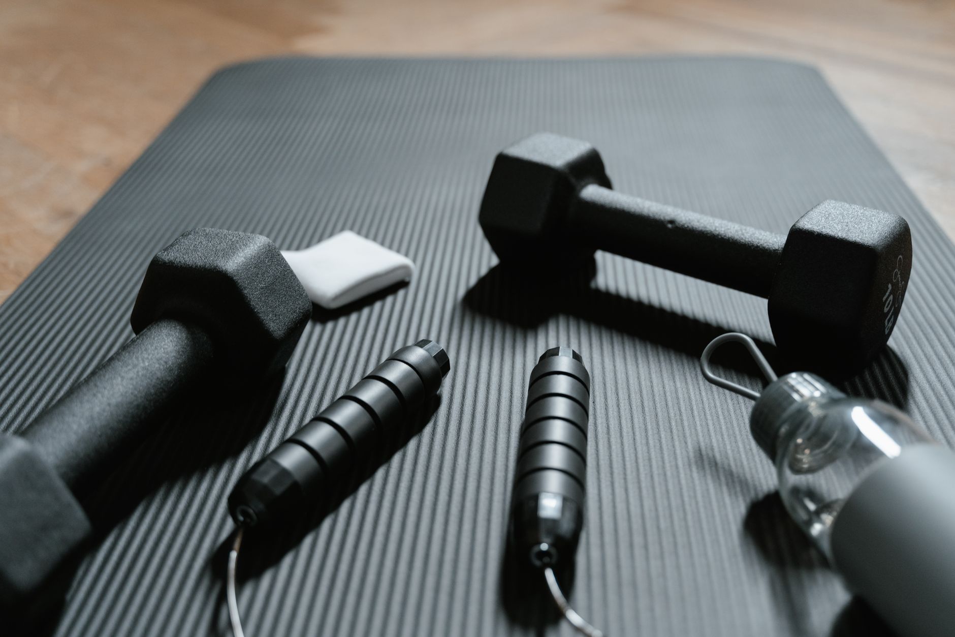 dumbbells and a jumping rope on a yoga mat